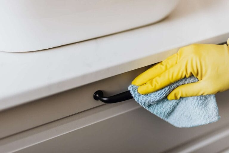 House cleaner cleaning handle of cabinet with microfiber cloth
