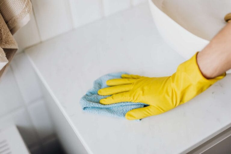 cleaner with gloved hand cleaning the bathroom sink