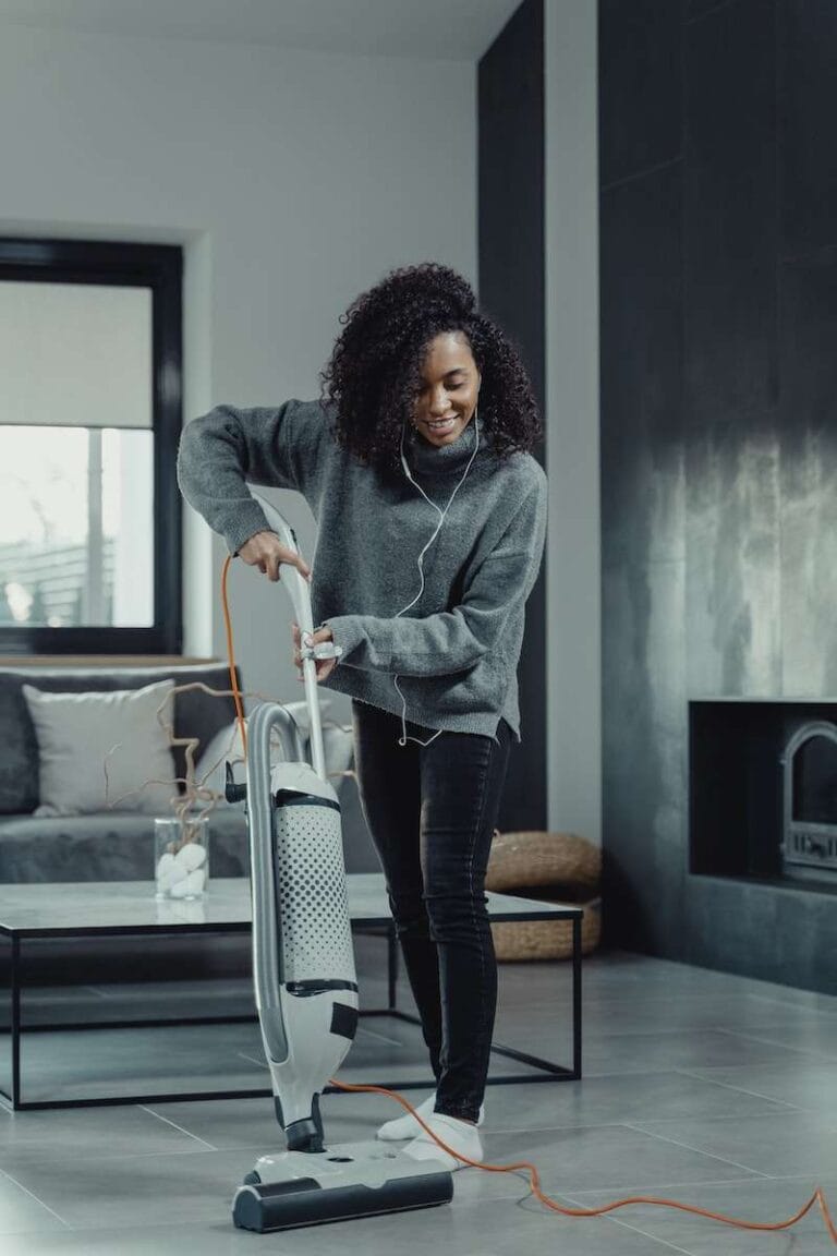 A Woman in Gray Sweater Using a Vacuum Cleaner