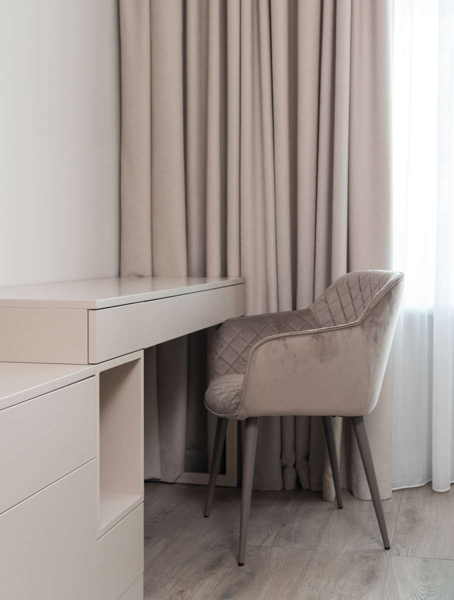 Interior of modern light room with table near chair and window with curtains