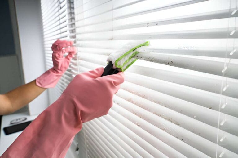 close up view of gloved hands cleaning the blinds