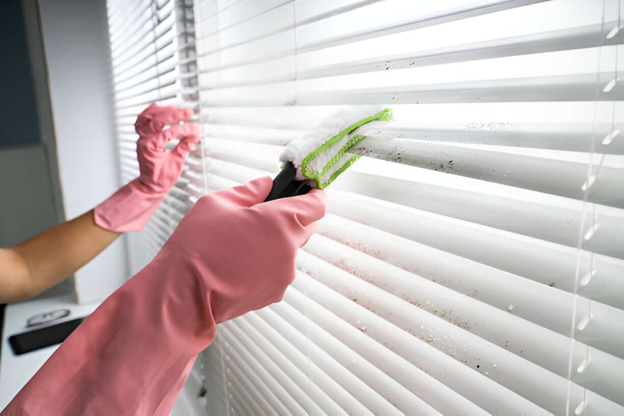 close up view of gloved hands cleaning the blinds