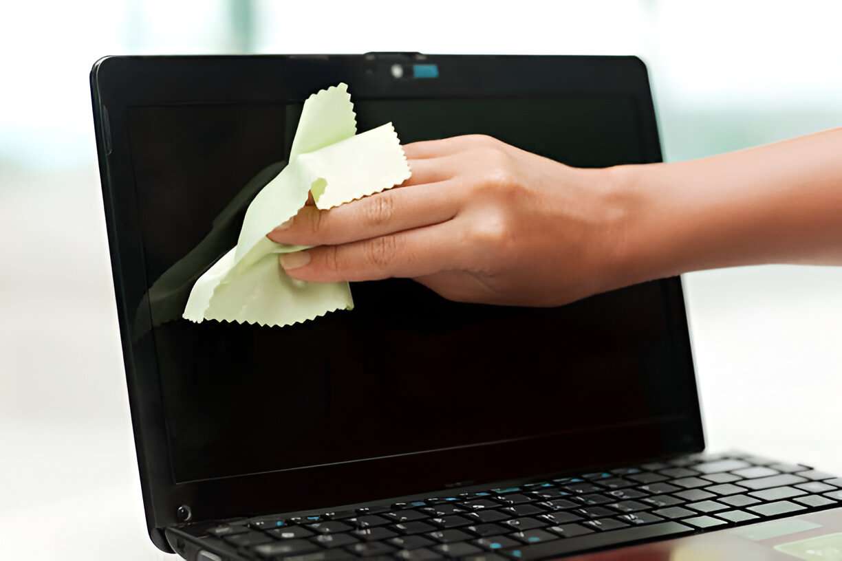 person cleaning a laptop screen